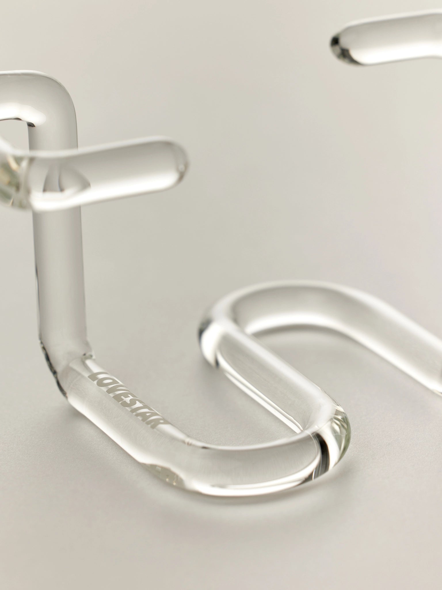 Close-up of a clear glass vase stand with 'Lovestar' branding on a white background